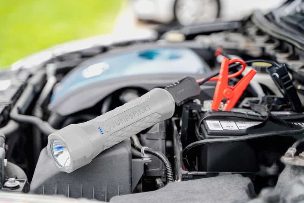 Small gray flashlight device attached to a battery that will start your car and is recommended as one of the things to bring on a road trip.