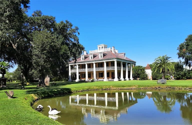Houmas House, a haunted Louisiana plantation, is reflected in the water of a pond.