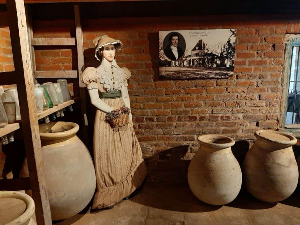 The basement at Laura Plantation shows a cutout of a woman and large old urns against the brick wall.