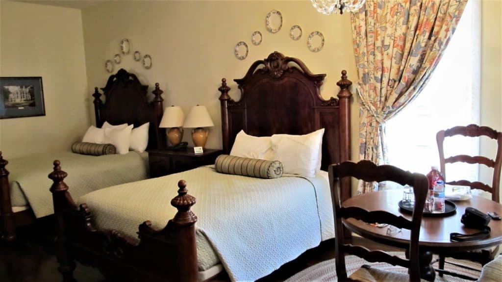 Two beds and a table in a cottage at Nottoway Plantation in White Castle, LA. The bed headboards are ornate dark wood.