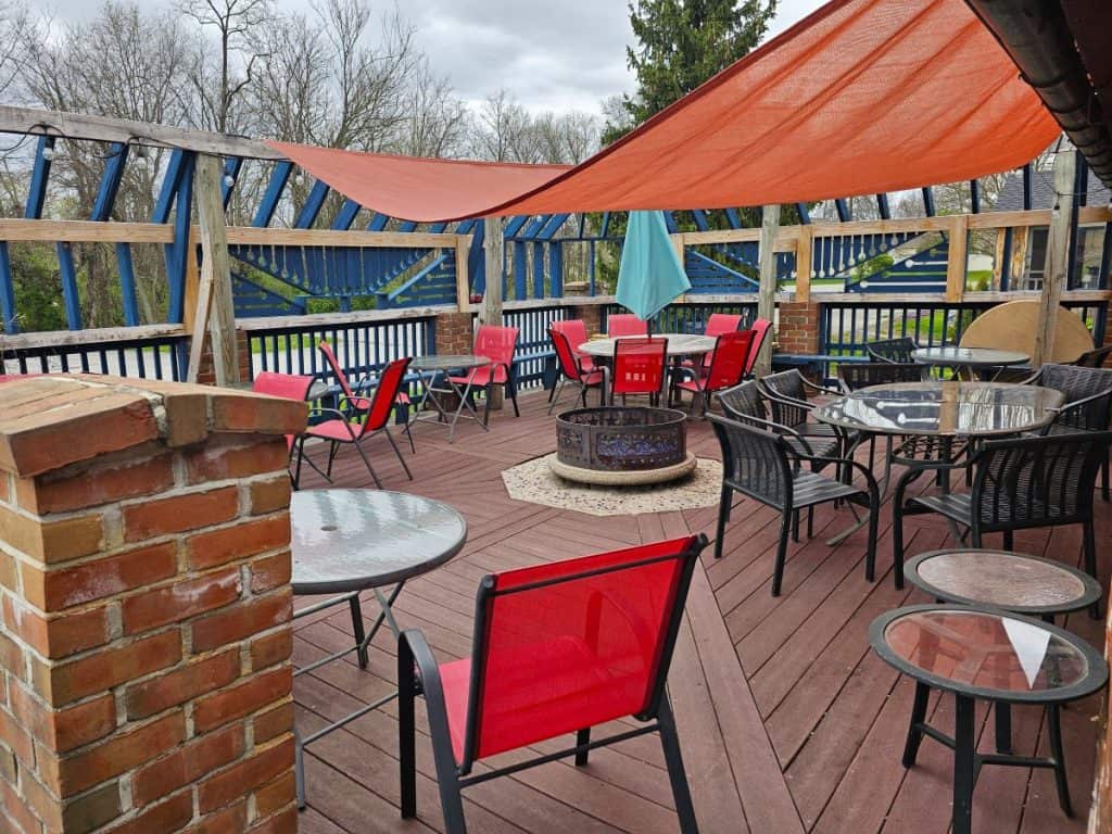 Outside seating at Gettysburg Battlefield Brew Works is read chairs and tables and a red canopy on a wide open patio.