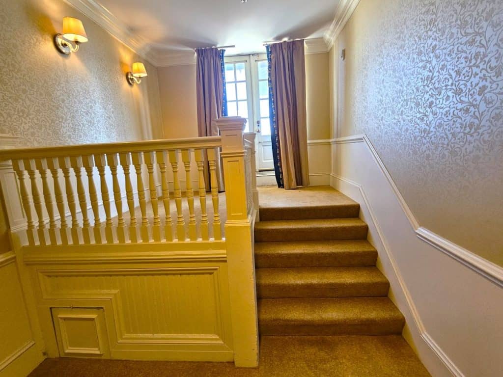 Five steps go to a landing and then a French type door with glass pains. The carpet and drapes are gold.