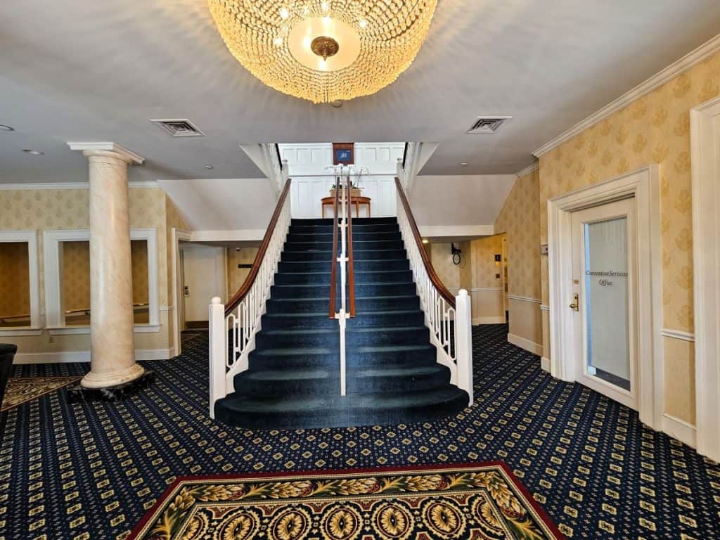 Stairs above the Grand Ballroom at The Jefferson Hotel, shows blue carpet and a regal room.