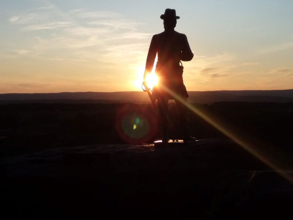 The statue of General Warren on LIttle Round Top with the sun setting.