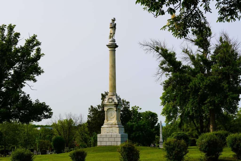 A large white statue with a soldier on the top overlooks the cemetery.