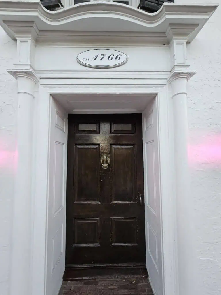A closeup of a wooden door embedded in a white building which is the Beekman Arms Inn.