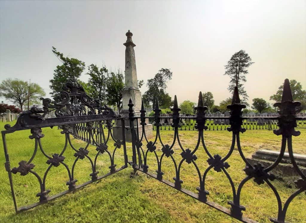 Wrought iron fence with a large white statue in the background.