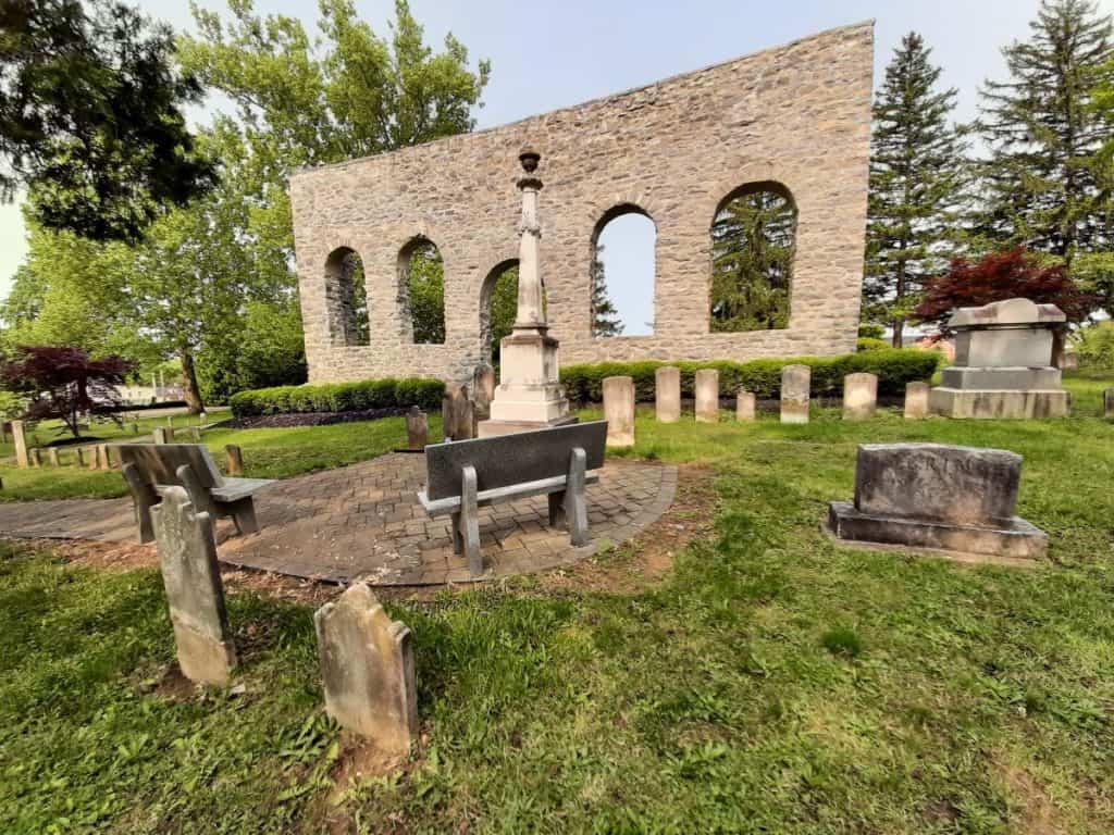 A sitting area with the old church wall at Mount Hebron Cemetery in the background.