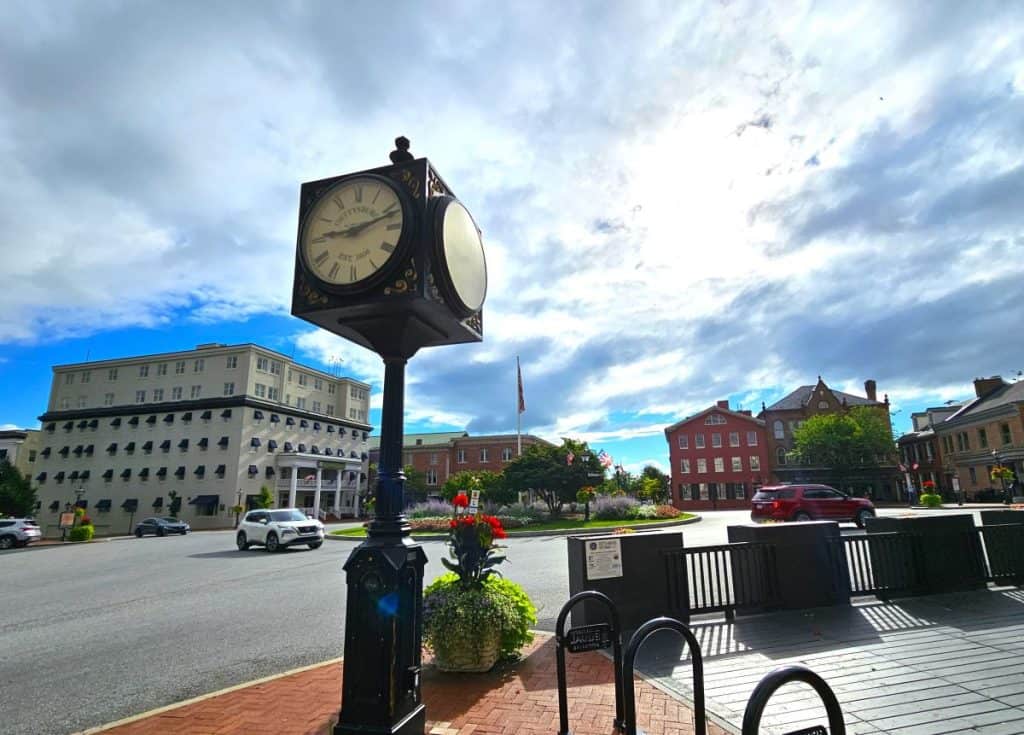 A town clock against a gray, cloudy sky, with the Hotel Gettysburg in the background.