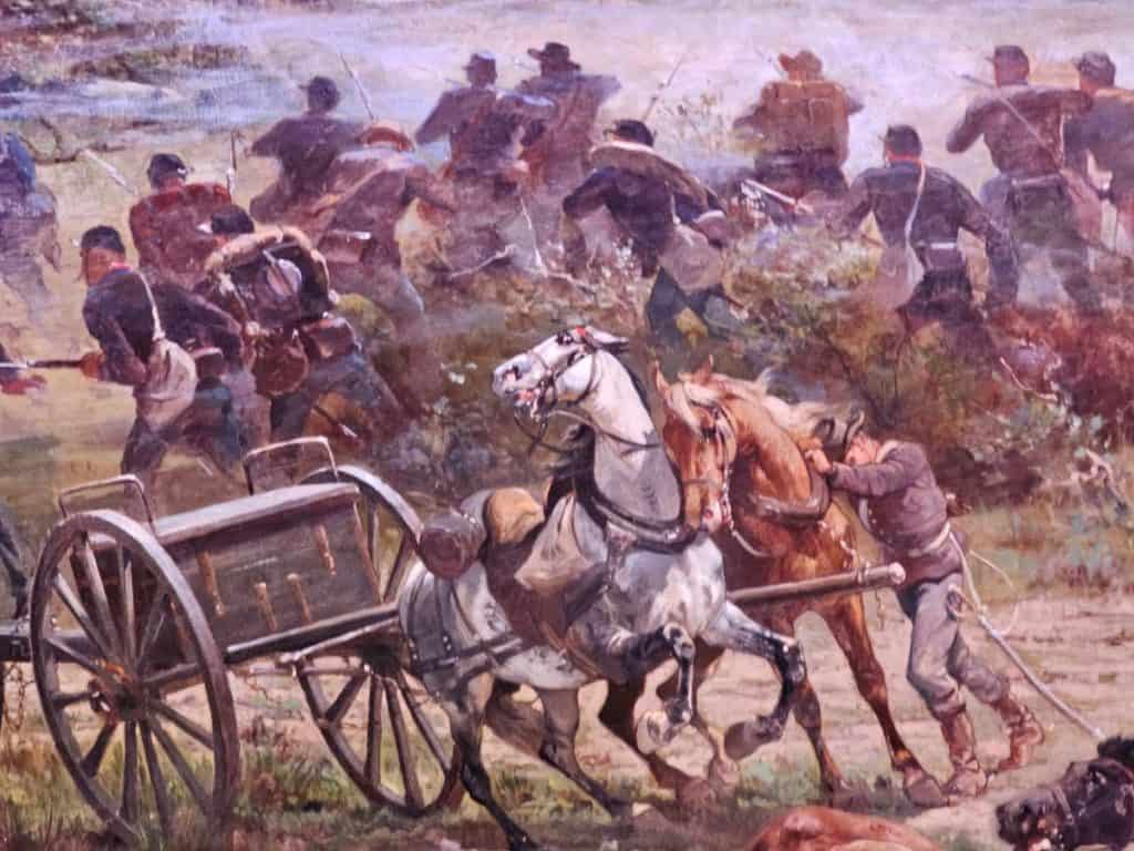 A closeup of a small scene of the Cyclorama painting showing two horses in a gun carriage with soldiers fighting behind.