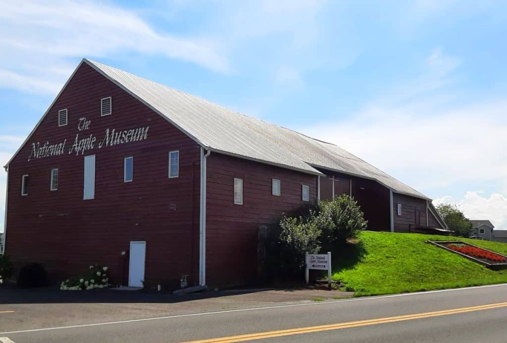 A large red barn that says Apple Museum against a blue sky.