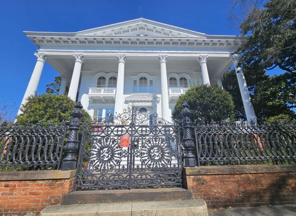 Bellamy Mansion is one of the must-see historic sites in Wilmington NC. This antebellum house is white with six white columns, and framed with an iron gate.