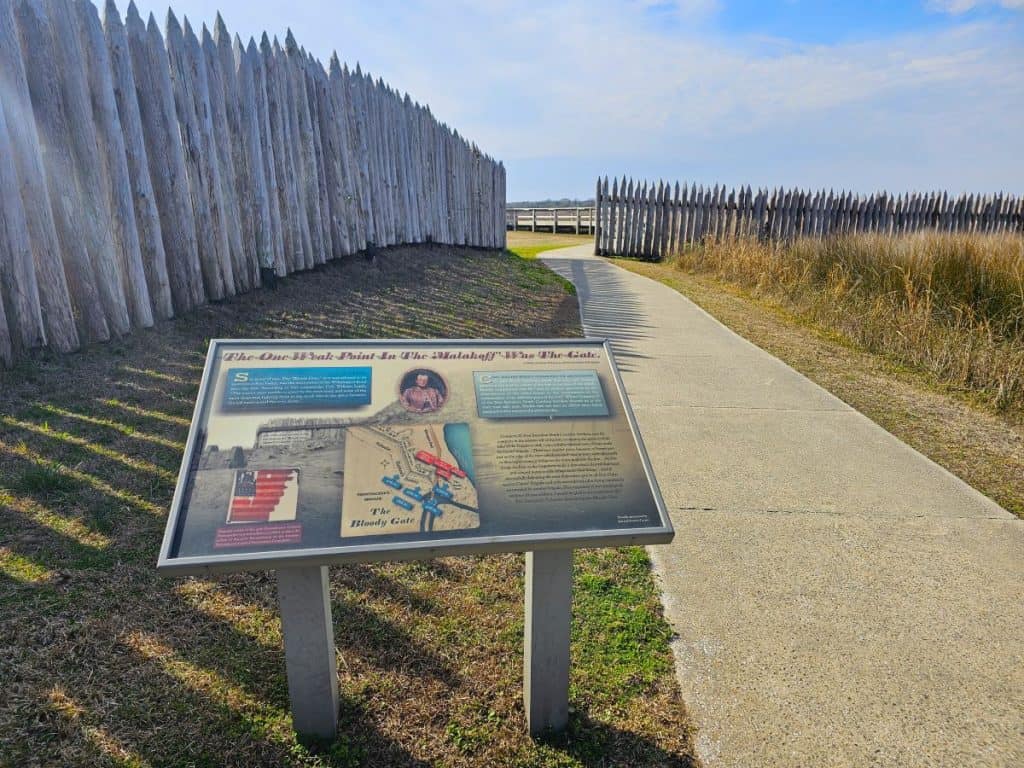 A wayside sign at Fort Fisher Civil War battlefield with the Gate of Death in the background.