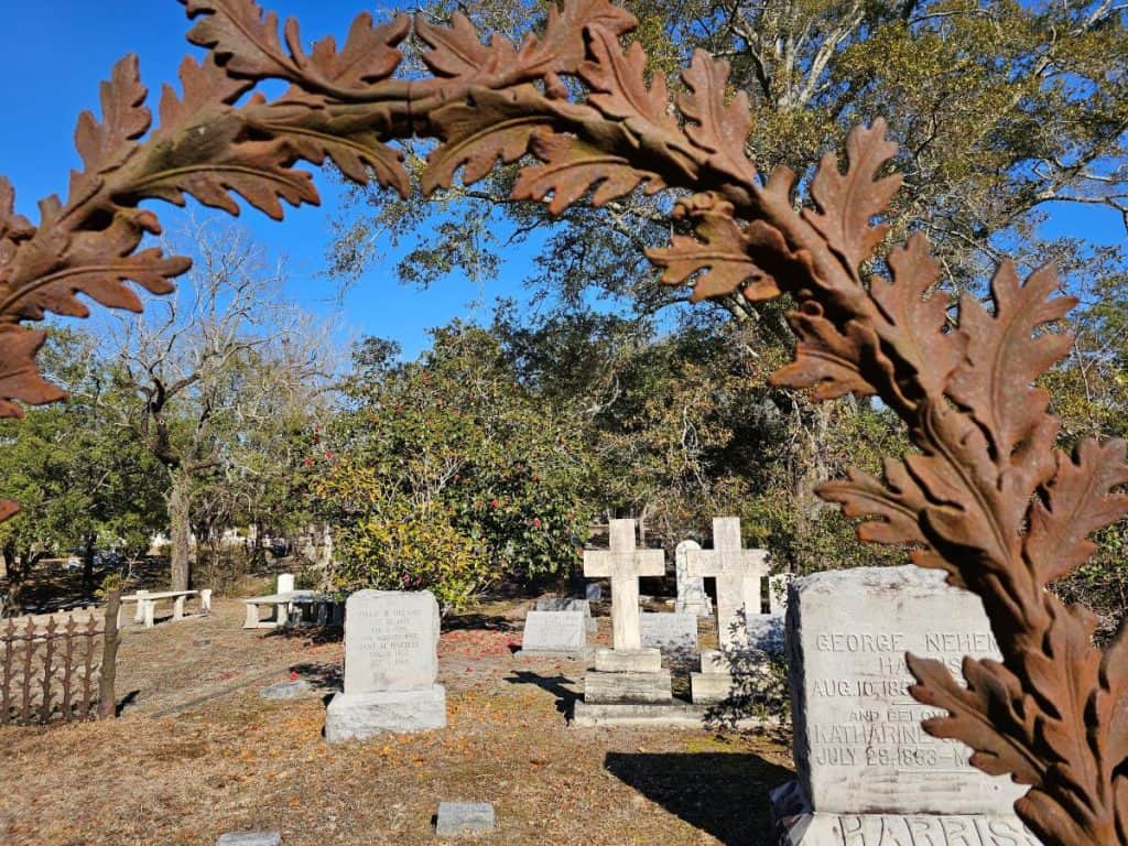 A wrought iron fence frames ancient gravesites at Oakdale Cemetery in Wilmington, NC.