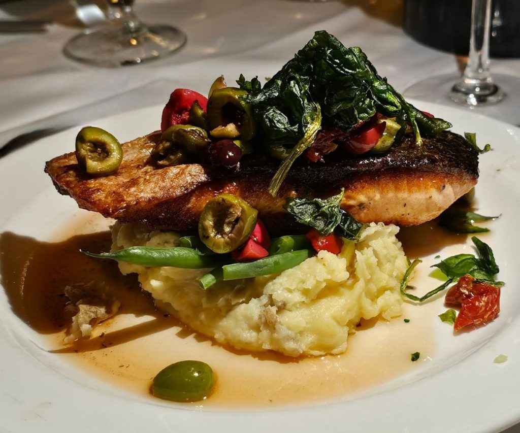 A salmon steak is stacked on top of mash potatoes and asparagus as part of a meal in Saratoga Springs.