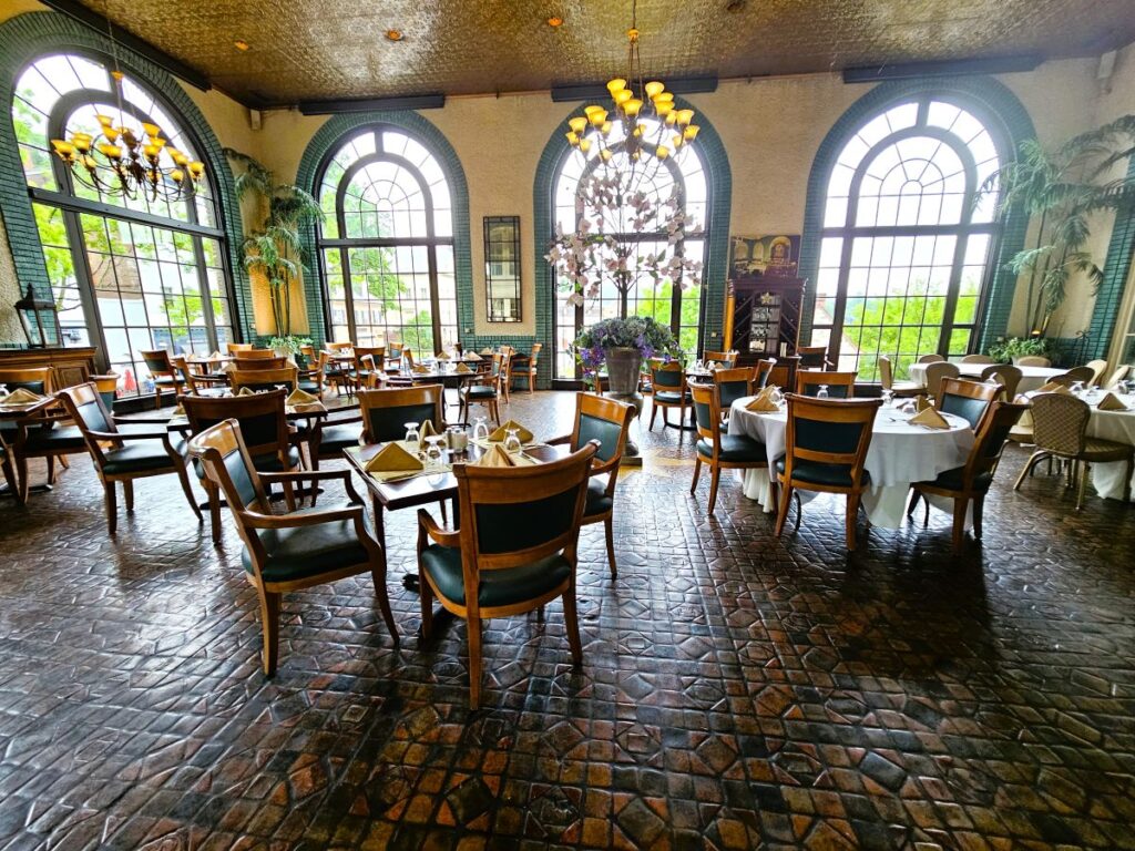 The dining room of the Hotel Bethlehem with large arched windows and tile floor.