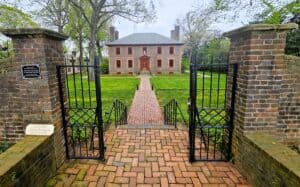 The front of the Revolutionary War era house The Wilton House, part of an America 250 itinerary. Shows the iron gates and brick sidewalks leading to the house.