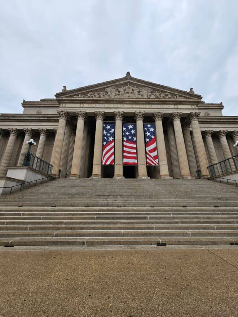 National Archives with steps and a red, white and blue patriotic banner.